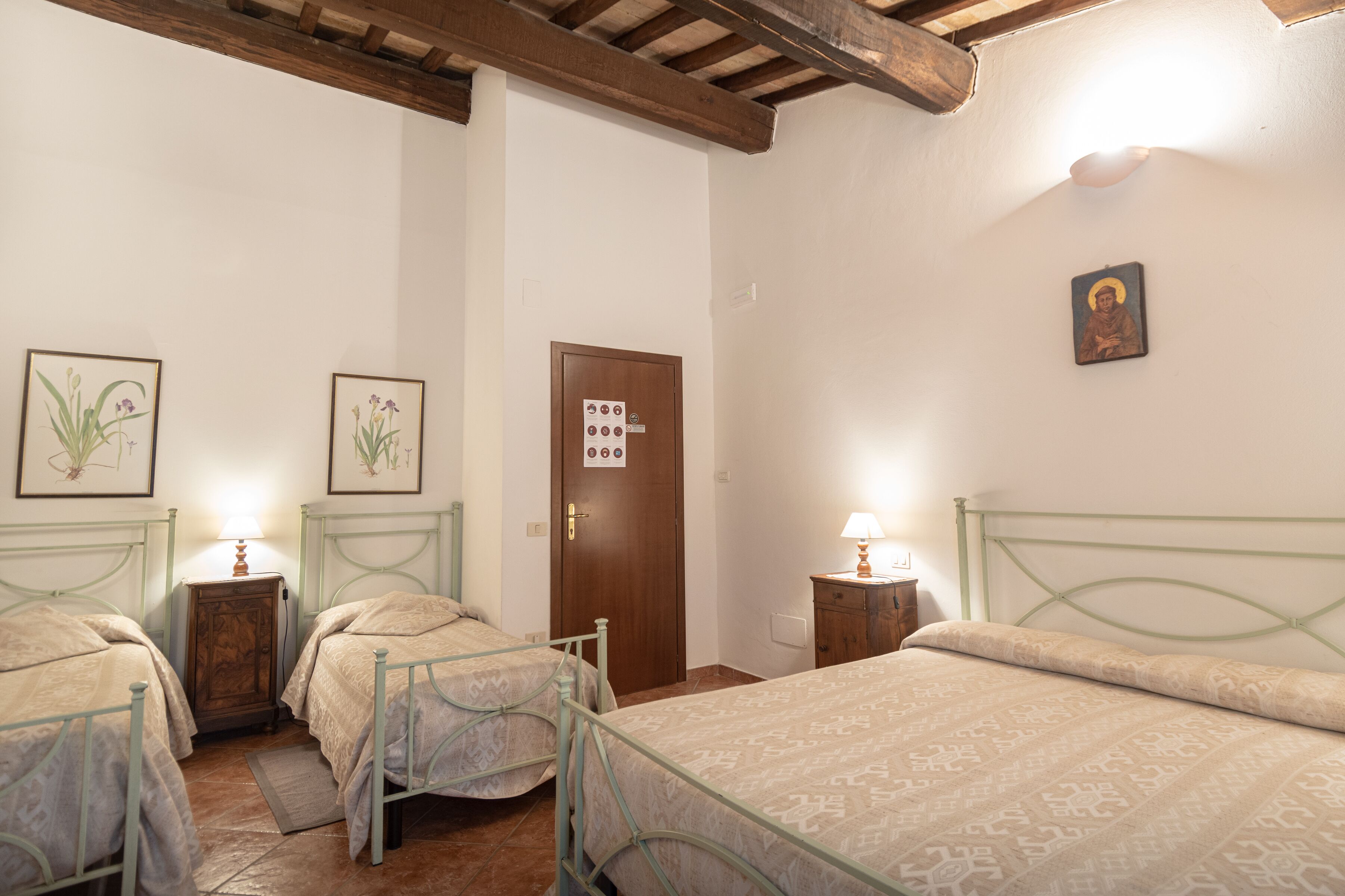 A room with two beds, a wooden door, and a small cabinet.