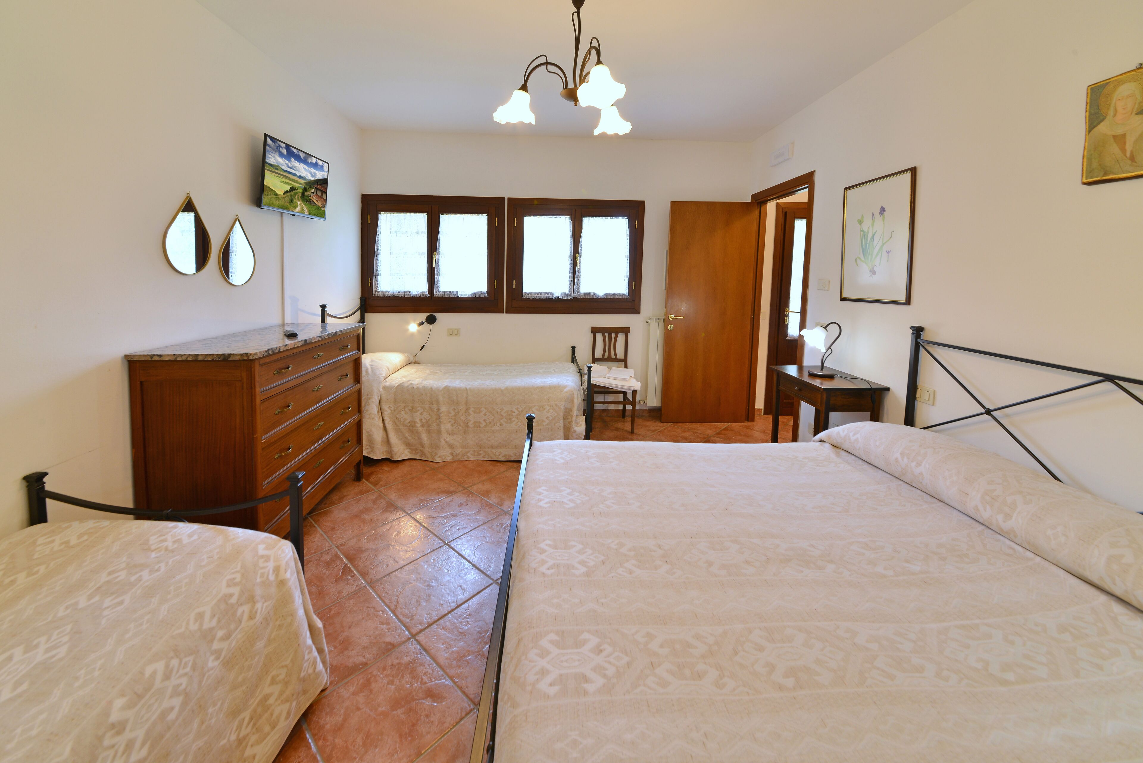 Un dormitorio con dos camas, un tocador, una silla y un escritorio con lámpara.