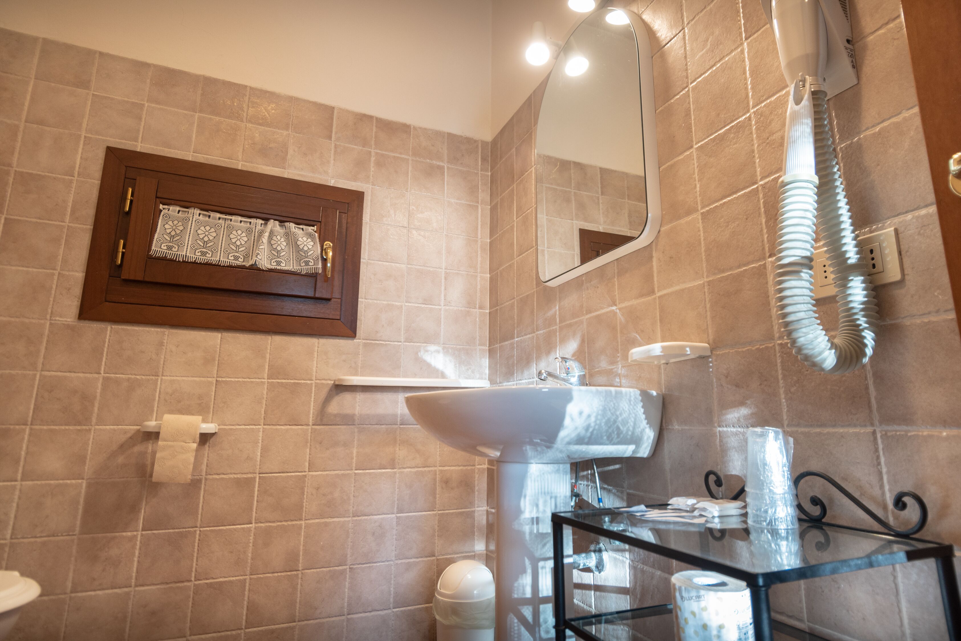 Un baño con lavamanos, espejo y perchero para toallas.