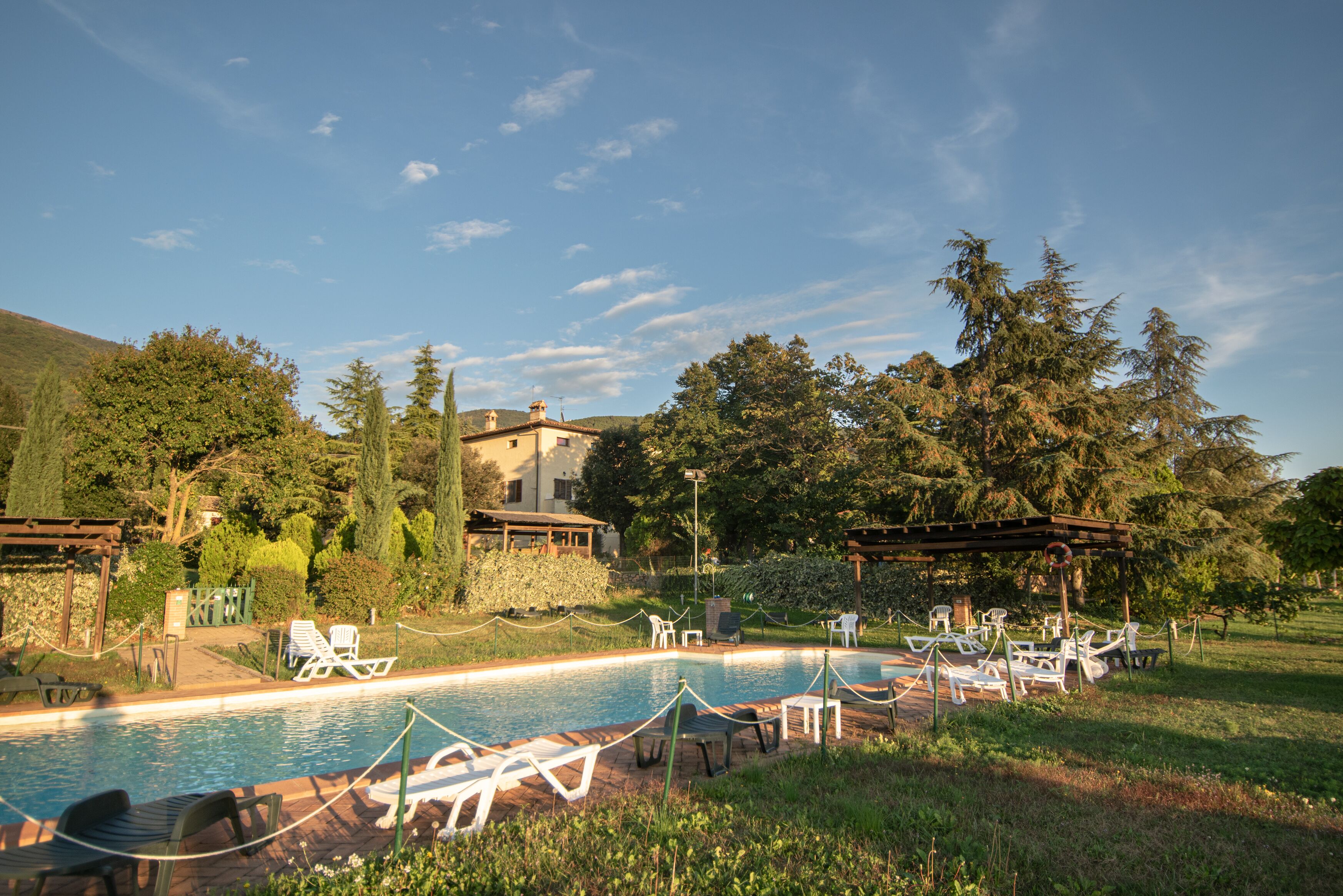 Un espace piscine avec des chaises longues et, en arrière-plan, un bâtiment en pierre.