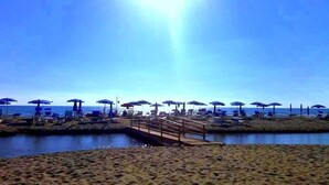 A beach with umbrellas and lounge chairs, a wooden bridge, and a calm sea. - Hotel Parco dei Principi (Capaccio-Paestum)
