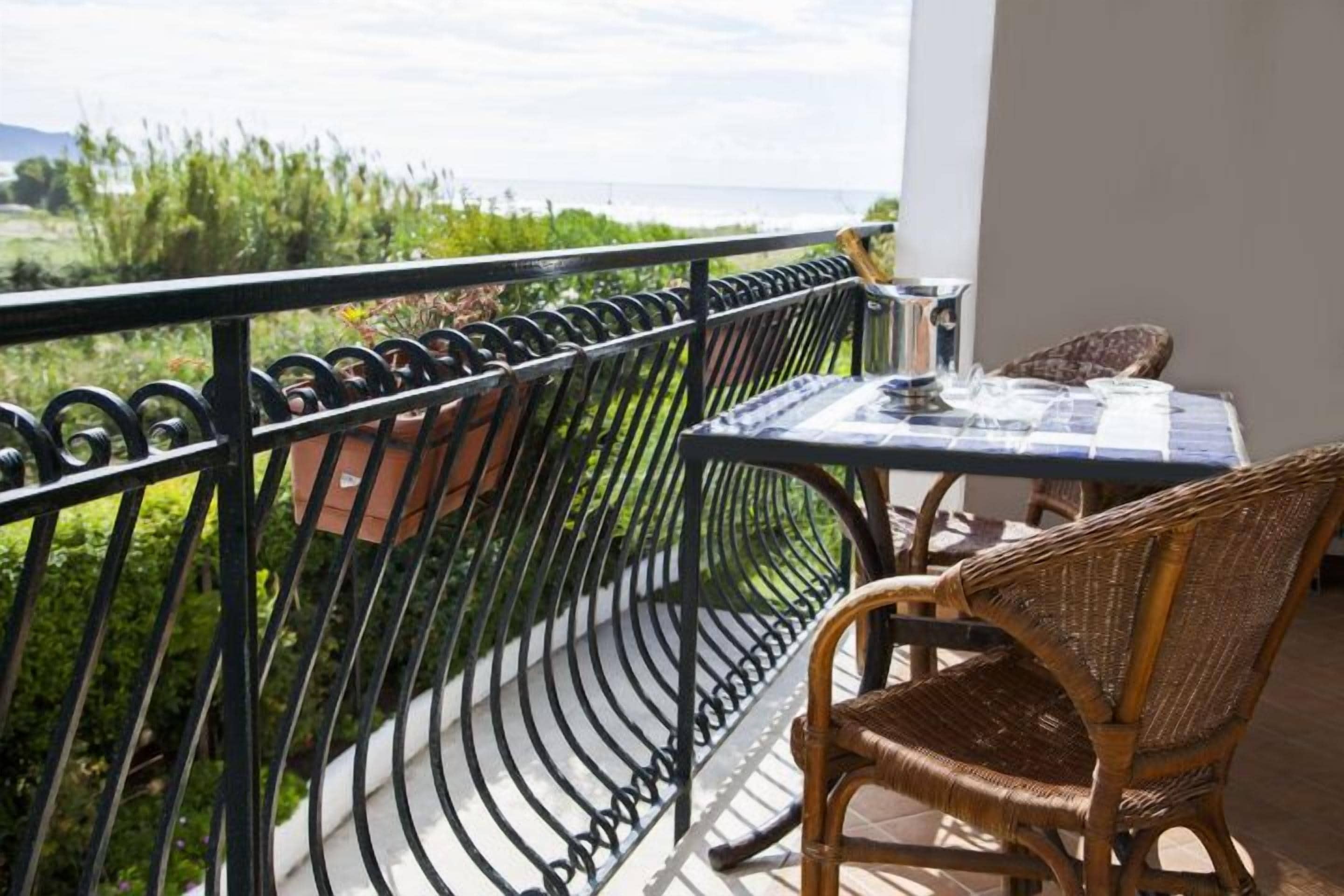 Een balkon met een tafel en stoelen, met uitzicht op een weelderig landschap.
