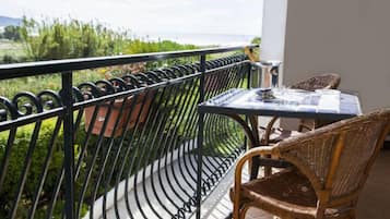 Een balkon met een tafel en stoelen, met uitzicht op een weelderig landschap.