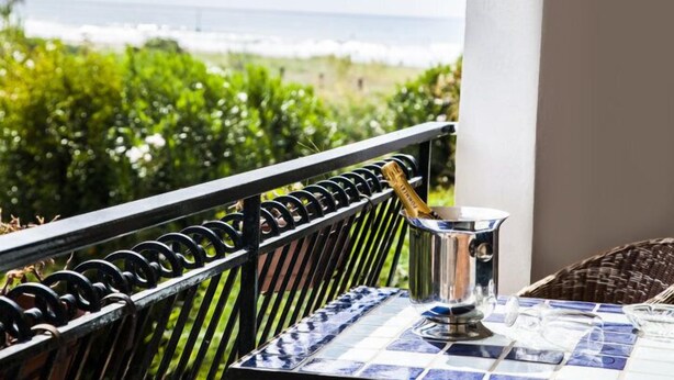 A balcony with a metal railing, a table with a blue and white patterned tablecloth, and a metal pitcher on the table. - Hotel Parco dei Principi (Capaccio-Paestum)
