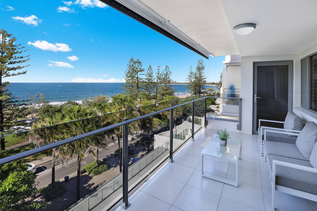 A balcony with a view of the ocean, a seating area with a table, and a door.