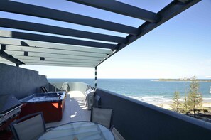 Un balcón con jacuzzi, mobiliario y vista al océano.