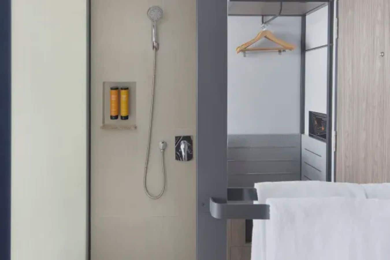 A bathroom with a shower, a towel rack, and toiletries.