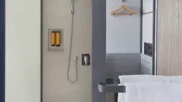 A bathroom with a shower, a towel rack, and toiletries.