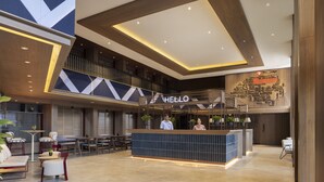A modern hotel lobby with a reception desk, seating area, and a staircase. - Travelodge Harbourfront (Singapore)