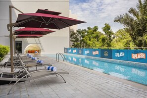 Una piscina al aire libre, sombrillas, sillones reclinables de piscina