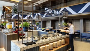 A buffet setup with a 'Social' sign, buffet counters, and a serving staff member. - Travelodge Harbourfront (Singapore)