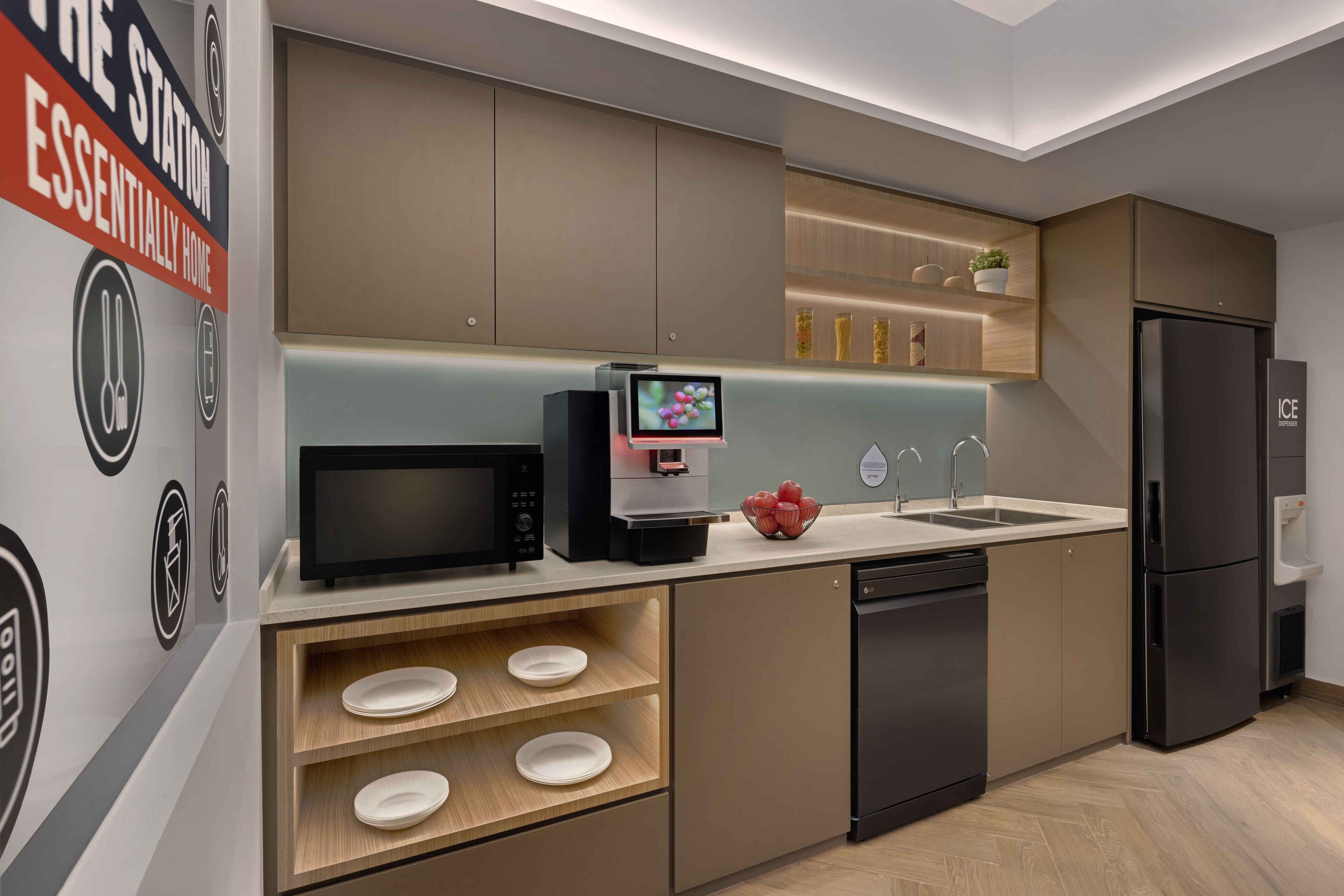 A modern kitchen with a built-in microwave, coffee machine, and a black refrigerator.