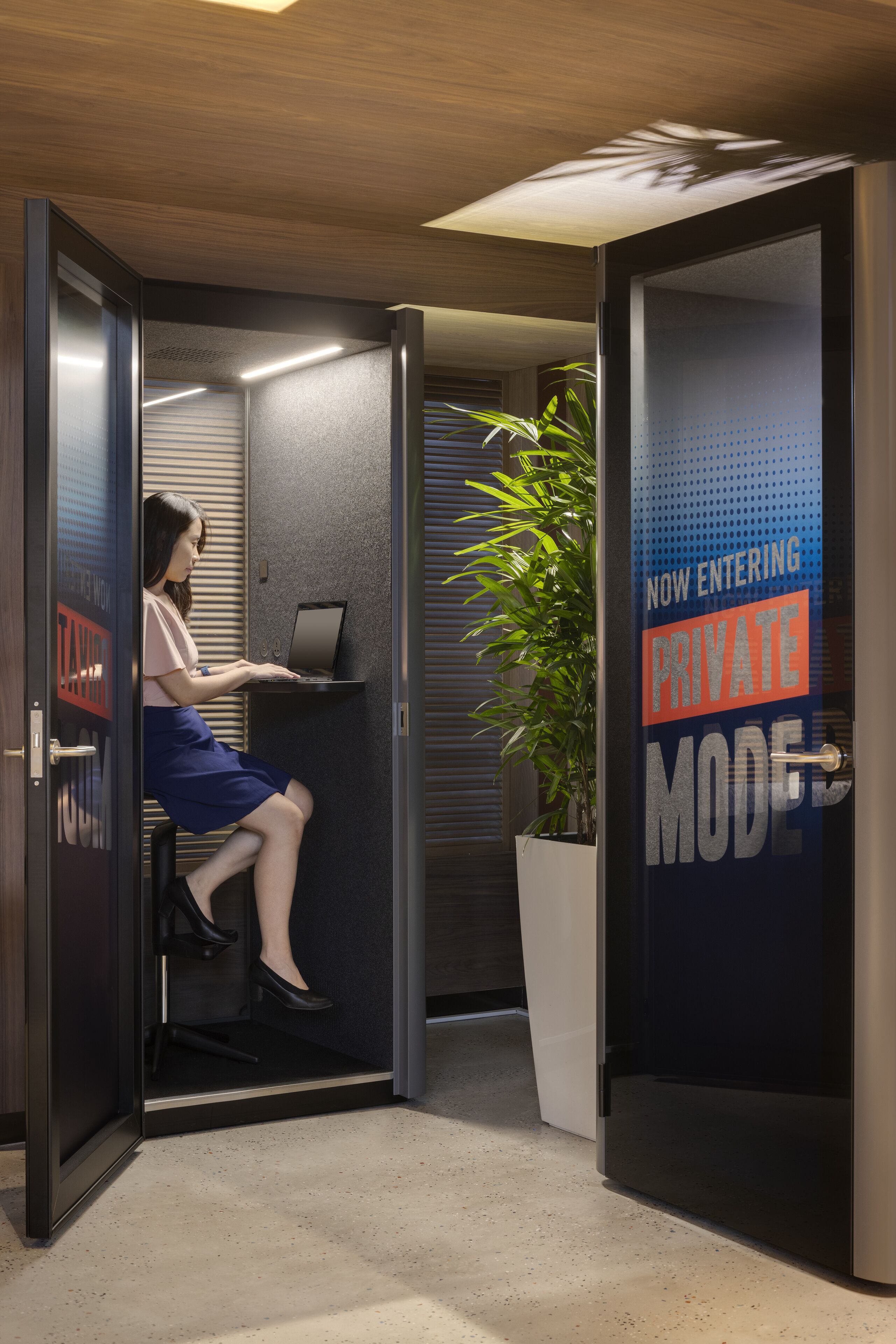 A woman working on a laptop in a private office with a sliding door.