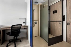 A modern bathroom with a shower, toilet, and a desk with a chair.
