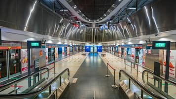 A modern train station with escalators, clear signage, and a central platform.