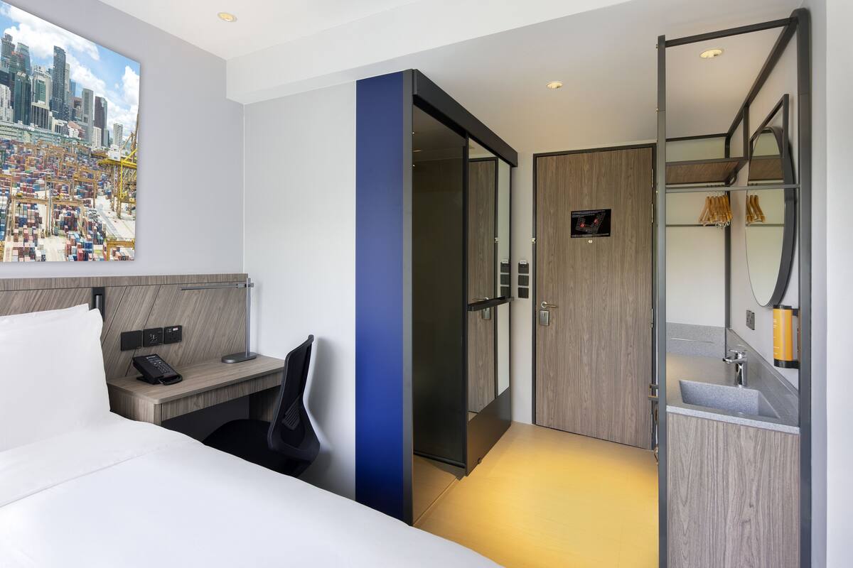Ein modernes Hotelzimmer mit Bett, Schreibtisch und großem Spiegel.