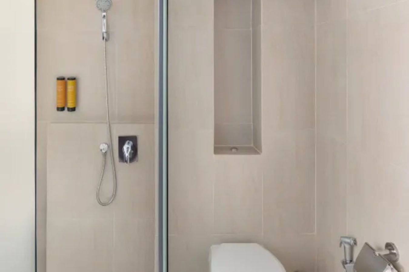 A bathroom with a shower, toilet, and a towel rack.