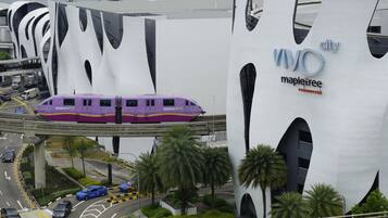 Un tren en una vía elevada pasando por un edificio moderno con el logo 'WOO'.