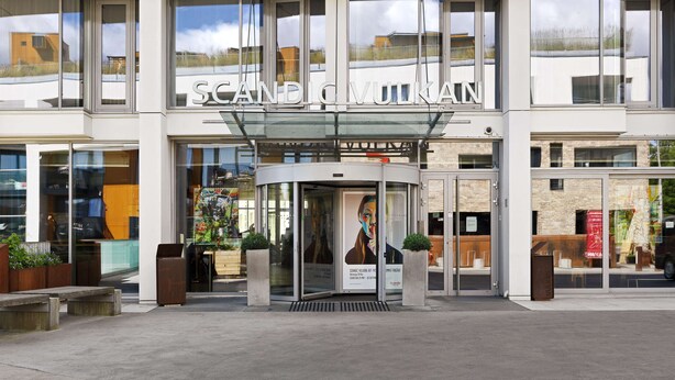 A modern building with a glass entrance and the name "SCANDIVUUKAN" displayed above. - Scandic Vulkan (Oslo)
