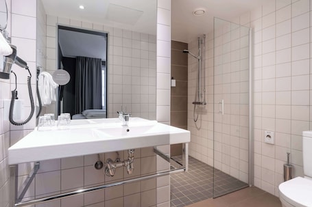 A modern bathroom with a large sink, a shower, and a toilet.