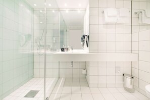 A modern bathroom with a glass-enclosed shower, a white sink, and a toilet.