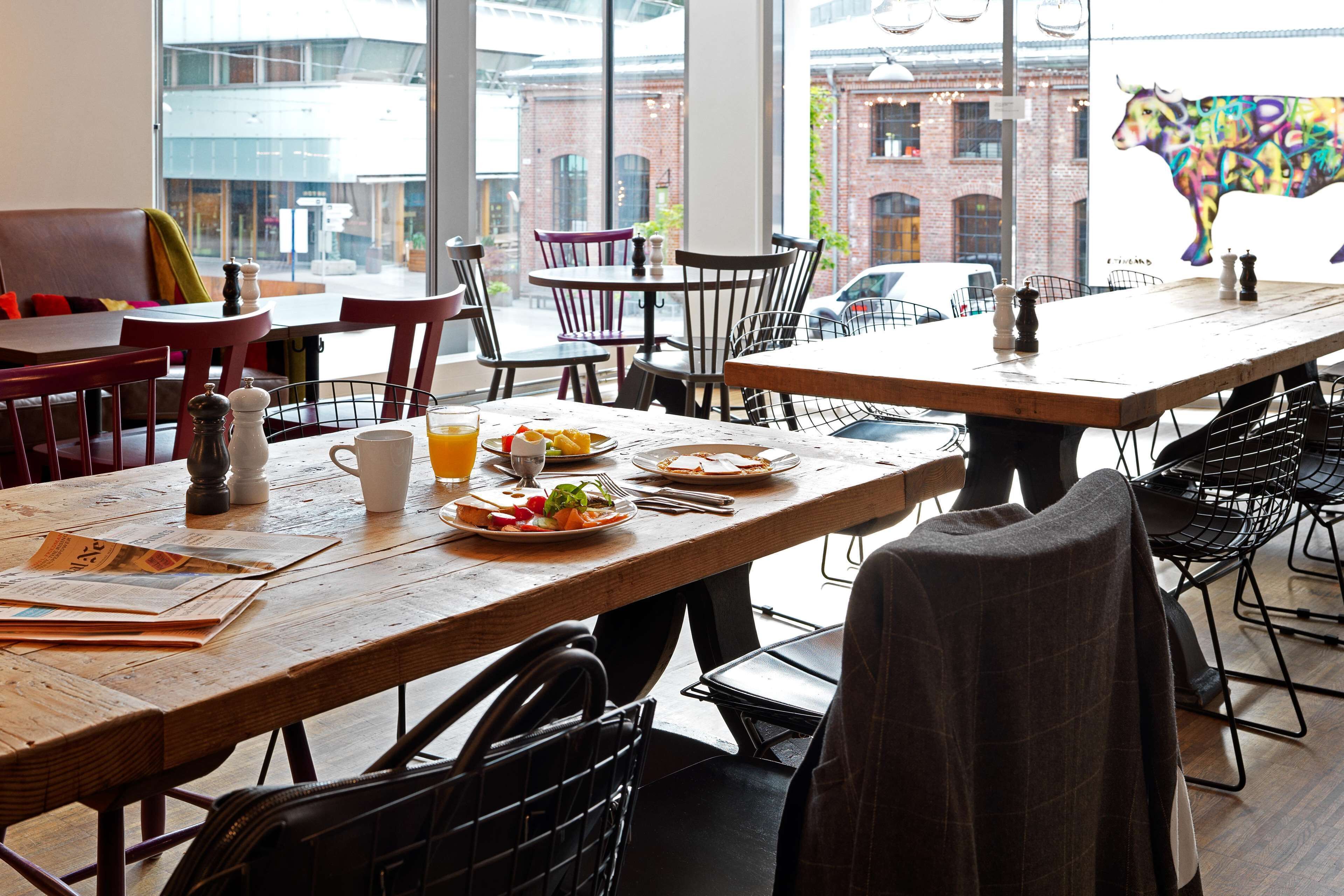 A dining area with wooden tables and chairs, a view of the street outside, and a colorful bull mural on the wall.