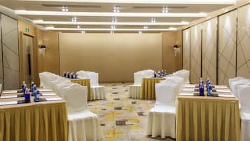 A conference room with round tables, white chairs, and water bottles.