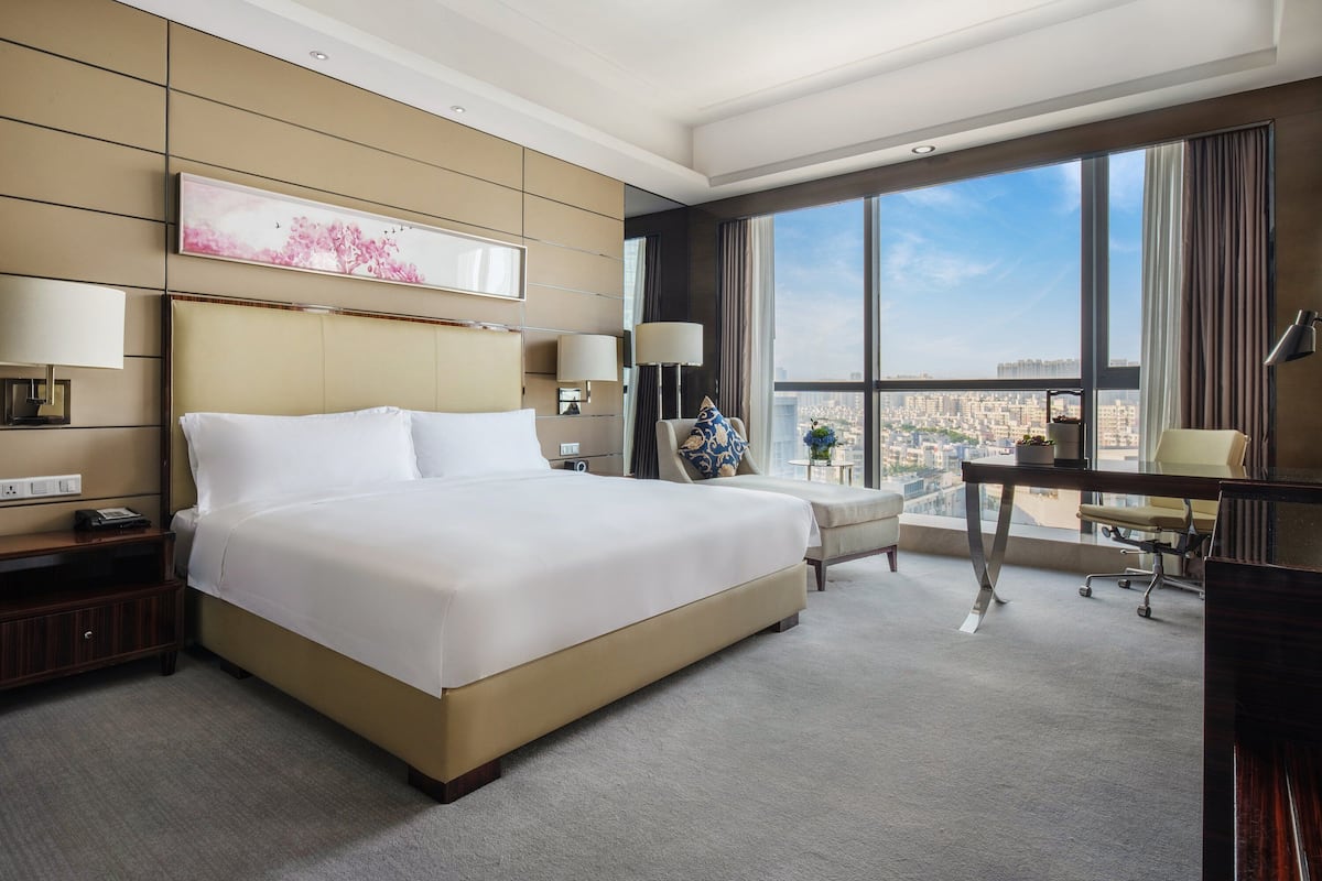 A hotel room with a large bed, a desk, and a view of the city.