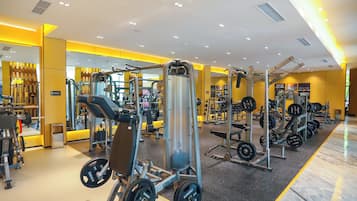 Une salle de sport équipée de divers appareils d’exercice, de miroirs et de supports pour les poids.