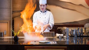 A chef in a white uniform cooking with flames on a grill. - Crowne Plaza Shenzhen Longgang City Centre by IHG (Shenzhen)
