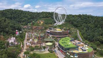 Vue aérienne d’un parc d’attractions avec une grande roue, diverses attractions et des bâtiments à thème.