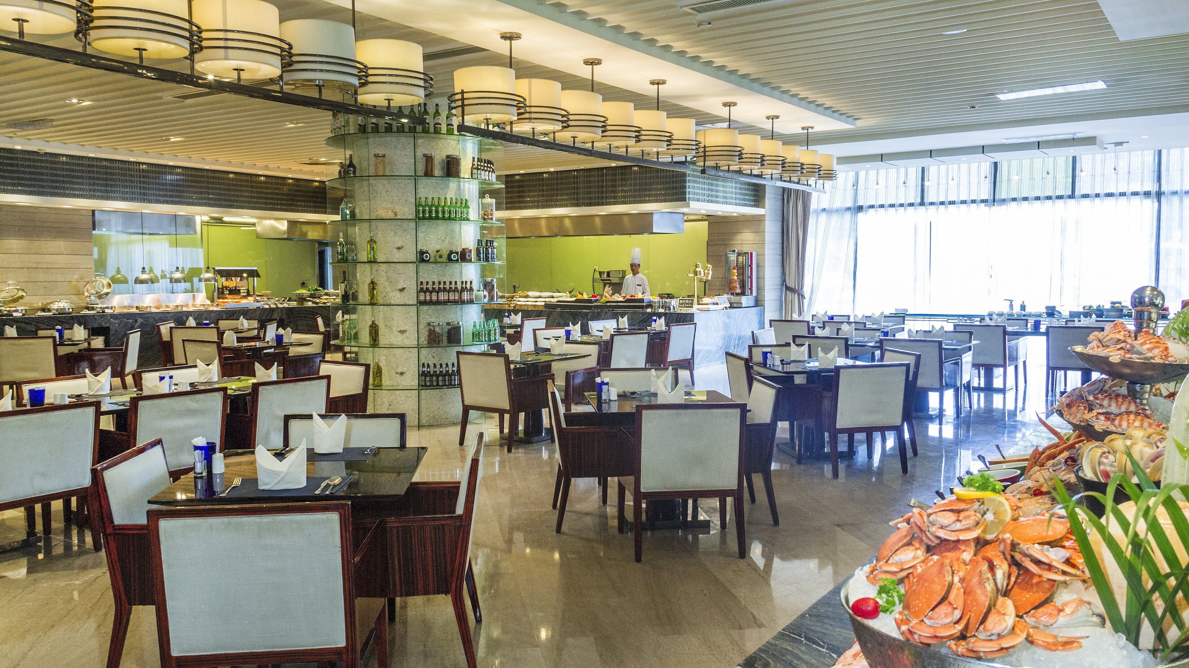 A spacious restaurant with multiple dining areas, a central bar, and a seafood display.