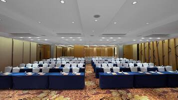 A conference room with rows of tables and chairs, equipped with water bottles and name cards.