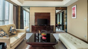A modern living room with a sofa, a coffee table, a TV, and a dining area with a table and chairs. - Crowne Plaza Shenzhen Longgang City Centre by IHG (Shenzhen)