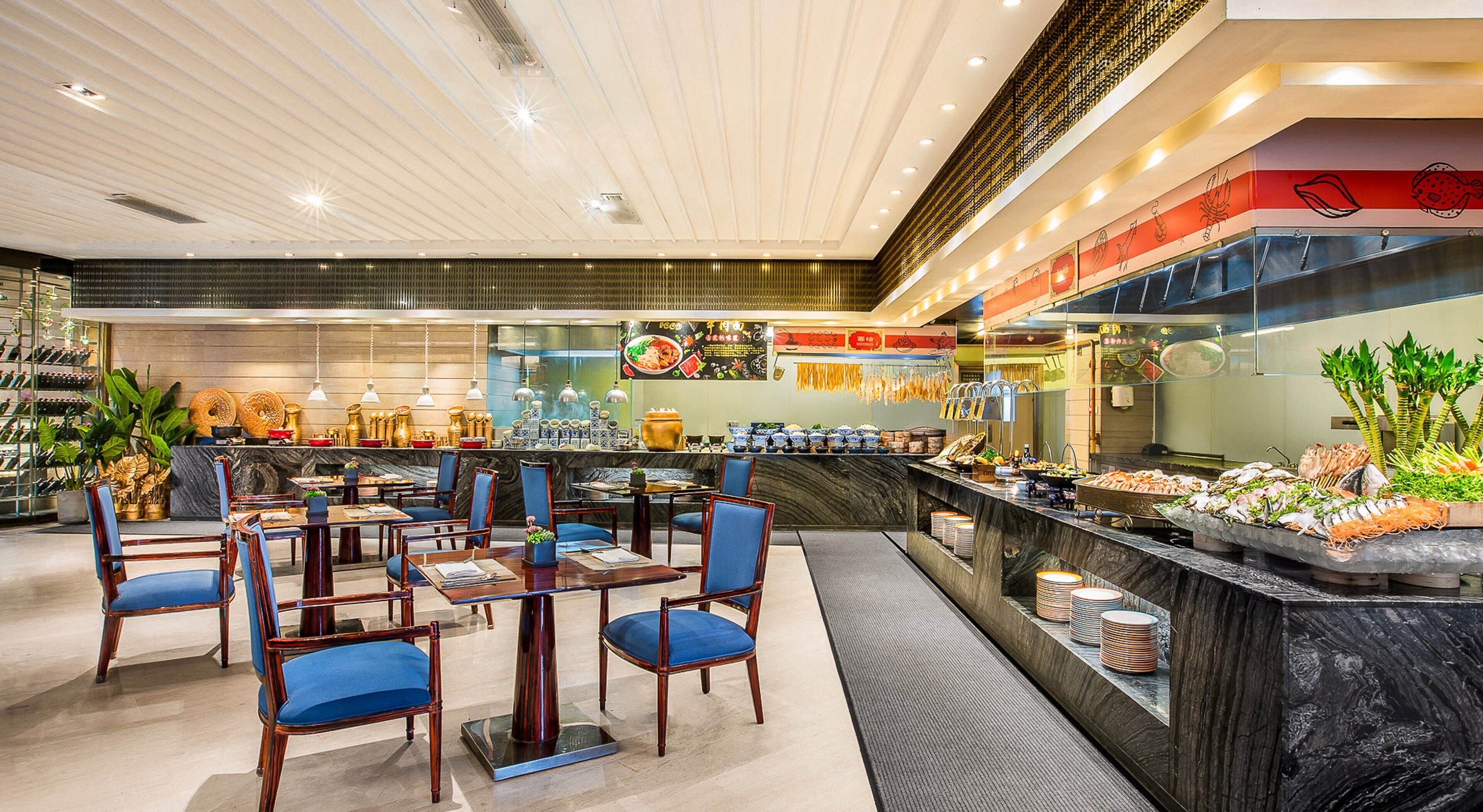 Un restaurant moderne avec un comptoir en marbre, des chaises bleues et une variété de plats exposés.