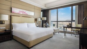 A modern hotel room with a large bed, a desk, and a view of the city. - Crowne Plaza Shenzhen Longgang City Centre by IHG (Shenzhen)