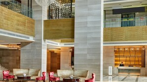A spacious lobby with a reception desk, a staircase, and a seating area with red chairs and a sofa. - Crowne Plaza Shenzhen Longgang City Centre by IHG (Shenzhen)