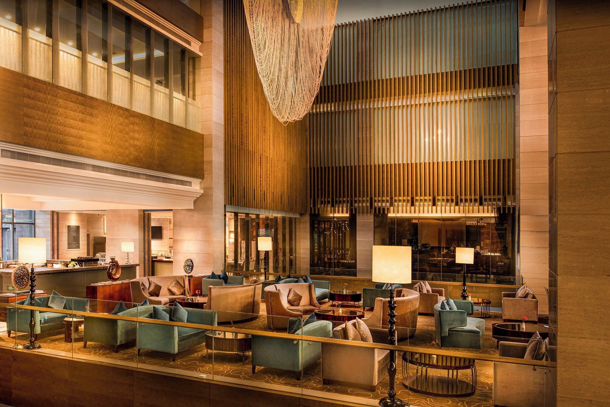 A spacious lobby with multiple seating areas, a large chandelier, and a view of the city through large windows.