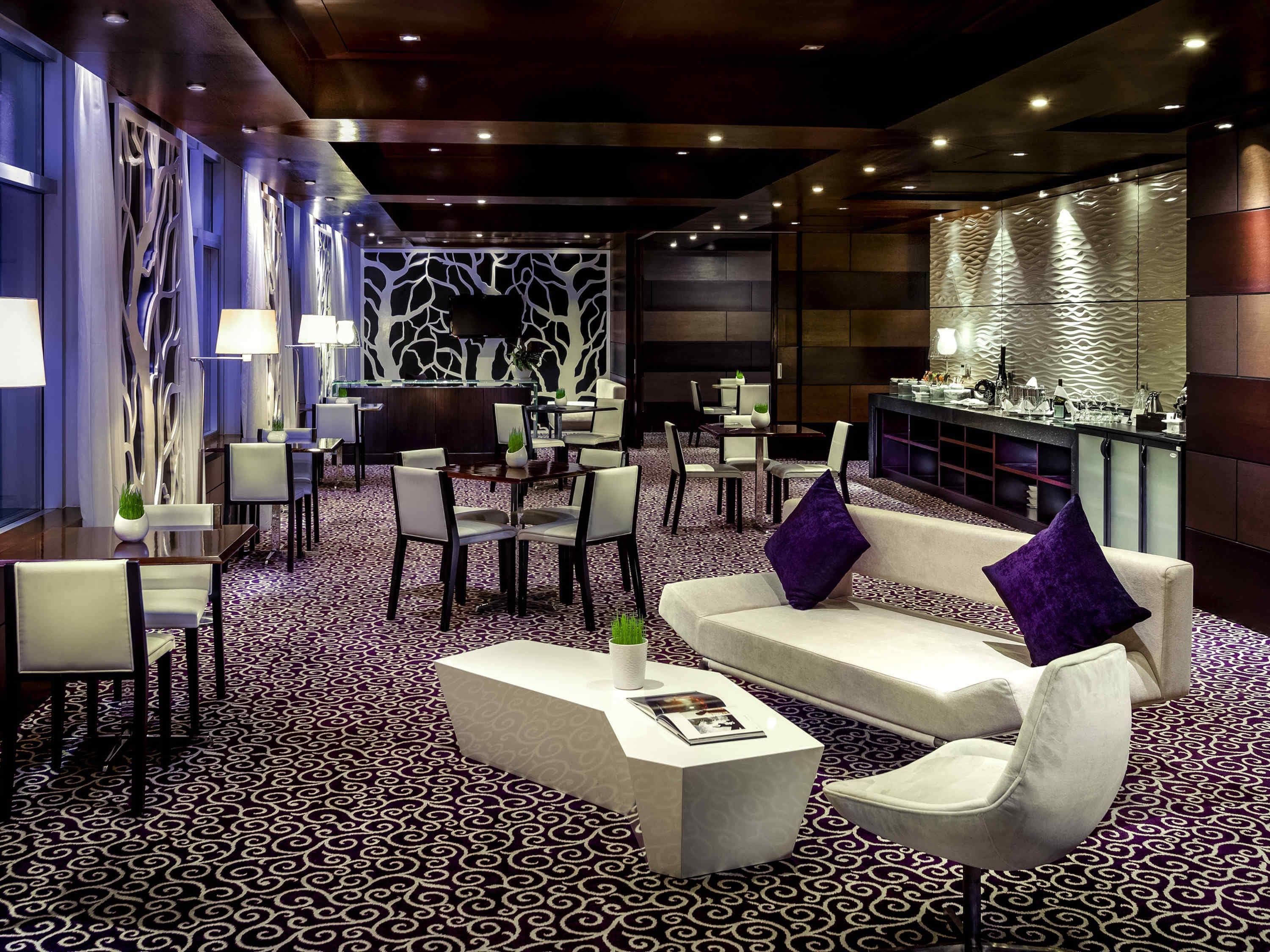 A modern lounge area with a patterned carpet, a bar, and seating arrangements.