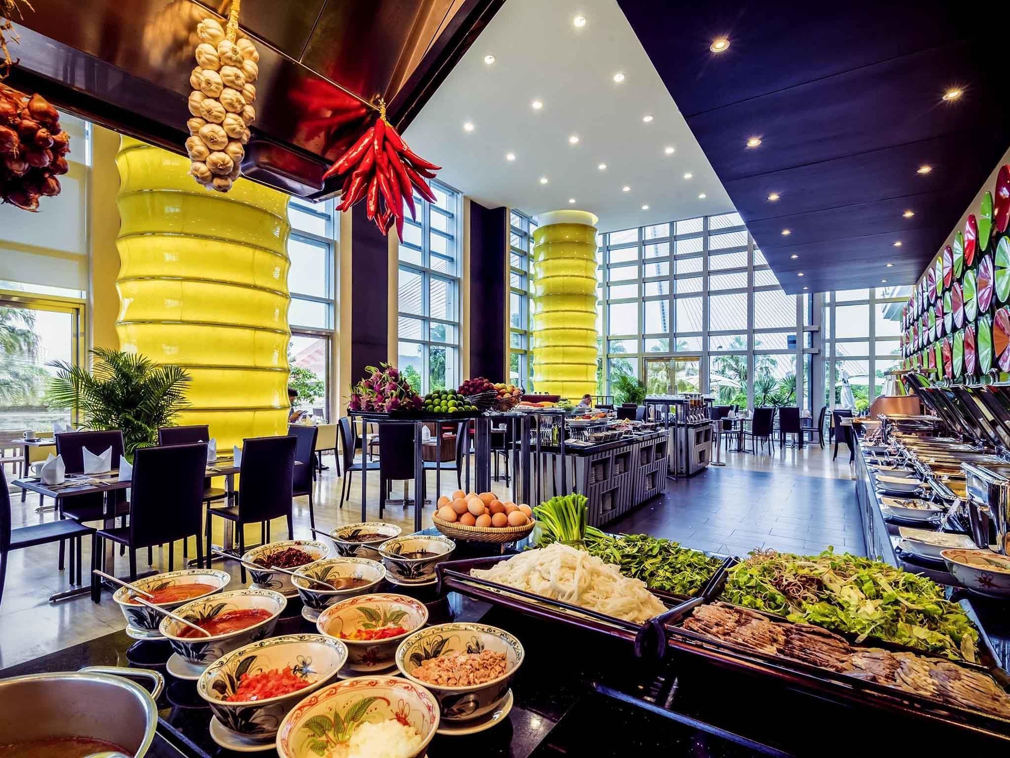 A buffet with various food items, a yellow pillar, and a large window.