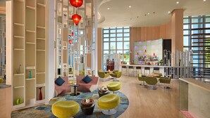 A modern bar area with a curved ceiling, a bar counter, and seating with round stools. - Grand Mercure Danang (Da Nang)