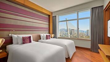 A hotel room with two beds, a large window with a city view, and a modern design.