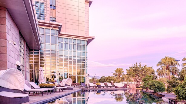 A modern hotel with a reflective pool, outdoor seating, and palm trees. - Grand Mercure Danang (Da Nang)