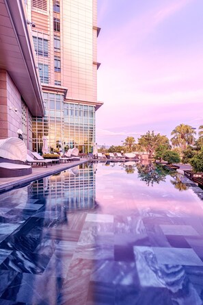 A modern hotel with a reflective pool, outdoor seating, and palm trees. - Grand Mercure Danang (Da Nang)