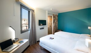 A hotel room with a bed, a desk with a laptop, a TV, and a shower area. - B&B HOTEL Marseille La Timone (Marseille)