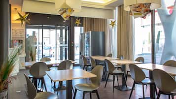 A modern restaurant interior with tables and chairs, large windows, and decorative star-shaped lights.