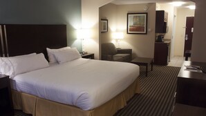 Een hotelkamer met een groot bed, nachtkastjes, een bureau, een stoel en een kleine kitchenette.