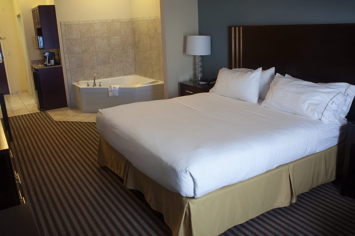 Ein Hotelzimmer mit einem großen Bett, einem Badezimmer mit einer Badewanne und einem Schreibtisch mit einer Lampe.