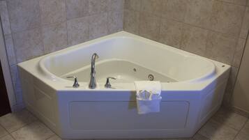 A corner bathtub with two faucets and a towel rack.