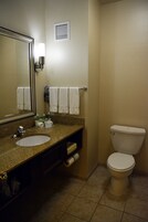 Un baño con lavamanos, espejo, toallero, inodoro y un ventilador de pared.
